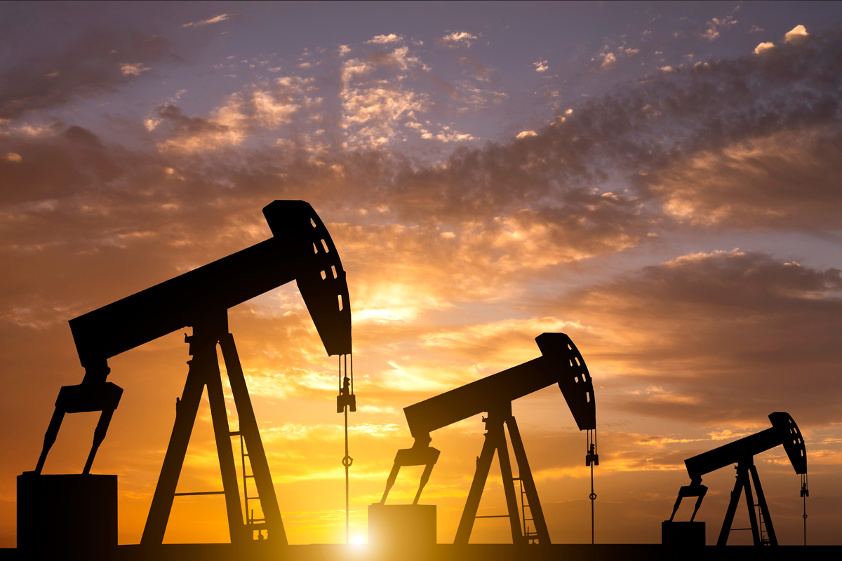 Oil pumpjacks silhouetted against a dramatic sunset sky.